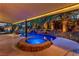 Luxurious pool and spa area with a rock waterfall feature, surrounded by lush palm trees and illuminated by accent lighting at 1509 Winslow St, Las Vegas, NV 89117