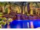 Beautiful swimming pool featuring a rock waterfall and mature palm trees, illuminated for nighttime enjoyment at 1509 Winslow St, Las Vegas, NV 89117