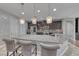 Close up of kitchen island with pendant lights, gray granite counters, and stainless steel appliances at 1727 Sonoran Bluff Ave, Henderson, NV 89014