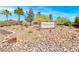 View of the 'Whitney Mesa Estates' sign and its surrounding landscape with palms, trees and rock ground cover at 1727 Sonoran Bluff Ave, Henderson, NV 89014