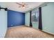Carpeted bedroom with a ceiling fan, a window with curtains, and a blue accent wall at 1792 Gentle Brook St, North Las Vegas, NV 89084