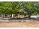 Front of the home with mature trees providing shade and a charming wooden fence at 2230 Wagon Ave, Pahrump, NV 89048