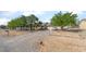 Well-kept single-story residence with a circular driveway, mature trees, and a charming fence at 2230 Wagon Ave, Pahrump, NV 89048