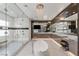 Contemporary bathroom with a soaking tub, a walk-in glass shower, large mirrors and marble countertops at 2610 Eldora Estates Ct, Las Vegas, NV 89117