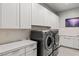 Modern laundry room with white cabinets, quartz countertop, and front load washer and dryer at 2610 Eldora Estates Ct, Las Vegas, NV 89117