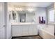 Bright bathroom featuring double sinks, a bathtub with subway tile surround, and window with shutters at 3002 Coveri Ct, Las Vegas, NV 89141