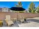 Relaxing patio features an umbrella, two wooden chairs, and vibrant potted plants at 3002 Coveri Ct, Las Vegas, NV 89141