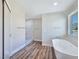 Bright bathroom featuring a modern soaking tub, wood-look floors, and a tiled shower at 3016 Mount Charleston Dr, Pahrump, NV 89048