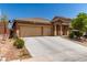 Charming single-story home featuring a desert landscape, wide driveway, and an attached two-car garage at 312 Purple Passion Ave, North Las Vegas, NV 89032