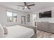 Bright bedroom with a ceiling fan, wood-look flooring, backyard view, and a modern dresser with a wall-mounted television at 360 Rosefinch St, Henderson, NV 89012