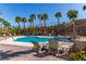 Luxurious community pool surrounded by lounge chairs, manicured landscaping, and towering palm trees at 360 Rosefinch St, Henderson, NV 89012