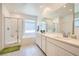 Bright bathroom featuring dual sinks, a bathtub, and a glass-enclosed shower with white cabinets at 4364 Contour Bend Ave, North Las Vegas, NV 89084