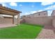 A private backyard offers an inviting covered patio and pristine artificial turf, creating a serene outdoor space at 5677 Asyma Ct, Las Vegas, NV 89113