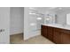 A full bathroom with dual sinks, cherry cabinets, a shower/tub combo and linen closet at 5677 Asyma Ct, Las Vegas, NV 89113