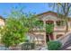 Tan two story condo with trimmed bushes and trees and stairway to upper units at 5751 E Hacienda Ave # 159, Las Vegas, NV 89122