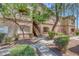 Tan two story condo with trimmed bushes and trees and stairway to upper units at 5751 E Hacienda Ave # 159, Las Vegas, NV 89122