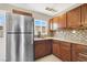 Charming kitchen featuring stainless steel appliances, wood cabinets, and a mosaic tile backsplash at 636 Burton St, Henderson, NV 89015