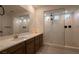 Modern bathroom featuring a glass-enclosed shower, a large mirror and a vanity with double sinks at 6486 Vanhoven Crest St, Las Vegas, NV 89166