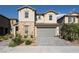 Charming two-story home with stone accents, desert landscaping, a gray two-car garage door, and a paver driveway at 6486 Vanhoven Crest St, Las Vegas, NV 89166