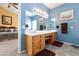 Bathroom with double sinks and blue walls leading to a bedroom with a beige wall at 672 Hitchen Post Dr, Henderson, NV 89011