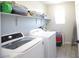 Efficient laundry room with modern appliances, shelving, tile floors and bright natural light at 7037 Tilligerry St, North Las Vegas, NV 89084