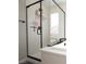 Modern bathroom featuring glass enclosed shower and tub with black trim and bright natural light at 7037 Tilligerry St, North Las Vegas, NV 89084
