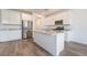 Bright kitchen features white cabinets, granite countertops, stainless steel appliances, island and wood-look floors at 7124 Sayonara Vista St, North Las Vegas, NV 89084