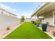 The artificial lawn is next to a covered patio with a fan and bistro set in this backyard at 7502 Lush Oasis Ave, Las Vegas, NV 89113