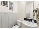 Stylish half bathroom featuring a modern sink, wainscoting, a decorative mirror, and tasteful decor at 7502 Lush Oasis Ave, Las Vegas, NV 89113