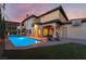 Inviting backyard oasis with a sparkling pool, patio, and beautifully landscaped outdoor living space at dusk at 761 Romano Ln, Henderson, NV 89012