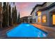 Stunning backyard featuring a modern pool with palm trees and lush greenery at twilight at 761 Romano Ln, Henderson, NV 89012