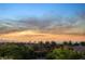 Expansive city view at sunset, complemented by verdant treetops and tropical palm trees at 761 Romano Ln, Henderson, NV 89012