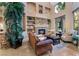 Living room with stone fireplace, built-in shelving, large windows, and neutral-toned walls at 761 Romano Ln, Henderson, NV 89012