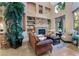 Living room with stone fireplace, built-in shelving, large windows, and neutral-toned walls at 761 Romano Ln, Henderson, NV 89012