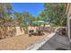 Inviting backyard featuring gravel, mature trees, privacy wall, and a patio area with grill and table at 8800 Crescent Ridge Ln, Las Vegas, NV 89134