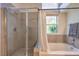 Bright bathroom boasts a tub, tiled shower, and natural light from the window at 8800 Crescent Ridge Ln, Las Vegas, NV 89134