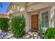 A welcoming front entrance with a solid wooden door and landscaped greenery at 8800 Crescent Ridge Ln, Las Vegas, NV 89134