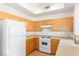 A kitchen featuring wood cabinets, a white refrigerator, and a white gas stove at 8805 Jeffreys St # 1003, Las Vegas, NV 89123