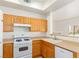 This kitchen features wood cabinets, white appliances, and a view into another room at 8805 Jeffreys St # 1003, Las Vegas, NV 89123