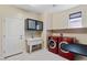 Functional laundry room with red front load machines, utility sink, and storage cabinets at 9240 Northfield Park Ct, Las Vegas, NV 89148