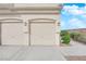 Three garage doors with decorative lighting feature a beige exterior in this townhome at 9315 Indian Corn Ct # 101, Las Vegas, NV 89178