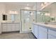 An elegant bathroom with dual sinks, quartz counters, a large mirror, and a tiled glass shower at 107 Barkset Way, Henderson, NV 89011