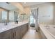 Bathroom featuring double sinks, a large mirror, tub, and access to the bedroom at 11289 Vision Peak Ave # 103, Las Vegas, NV 89135
