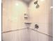Close-up of a walk in shower with white tiles, corner shelving and shower head at 135 E Harmon Ave # 809, Las Vegas, NV 89109