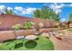 Backyard seating area features a charming table set, artificial turf, and desert landscaping at 15 Imposing Knoll Ave, Henderson, NV 89002