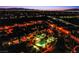 Aerial community view showcasing a pool, palm trees, and city lights in the background at 1557 Blue Sierra Ct, Henderson, NV 89074