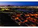 Aerial view of a community showcasing the homes and lake with illuminated city skyline at 1557 Blue Sierra Ct, Henderson, NV 89074