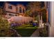 Serene backyard features lush artificial grass, a decorative rock garden, and cozy seating beneath ambient lighting at 1557 Blue Sierra Ct, Henderson, NV 89074