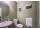Half bathroom features a pedestal sink, framed mirror, and toilet with a hidden paper storage at 1557 Blue Sierra Ct, Henderson, NV 89074