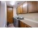 Efficient laundry room with wood cabinets, countertops, and modern stainless steel washer and dryer units at 1557 Blue Sierra Ct, Henderson, NV 89074